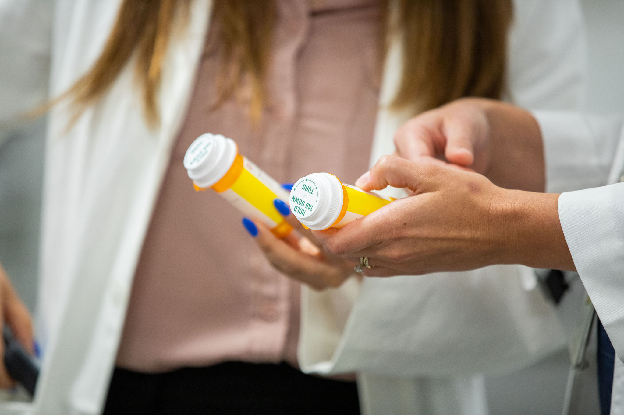 Two pharmacists holding and examining two amber medication vials
