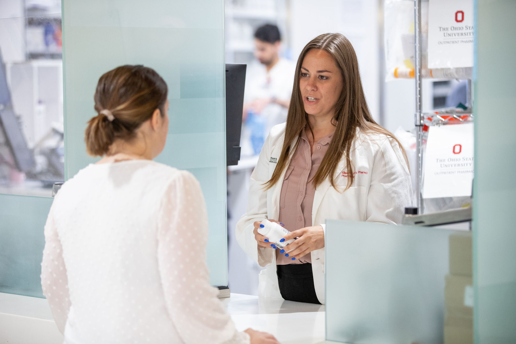 Pharmacist speaking to a patient at a counseling window