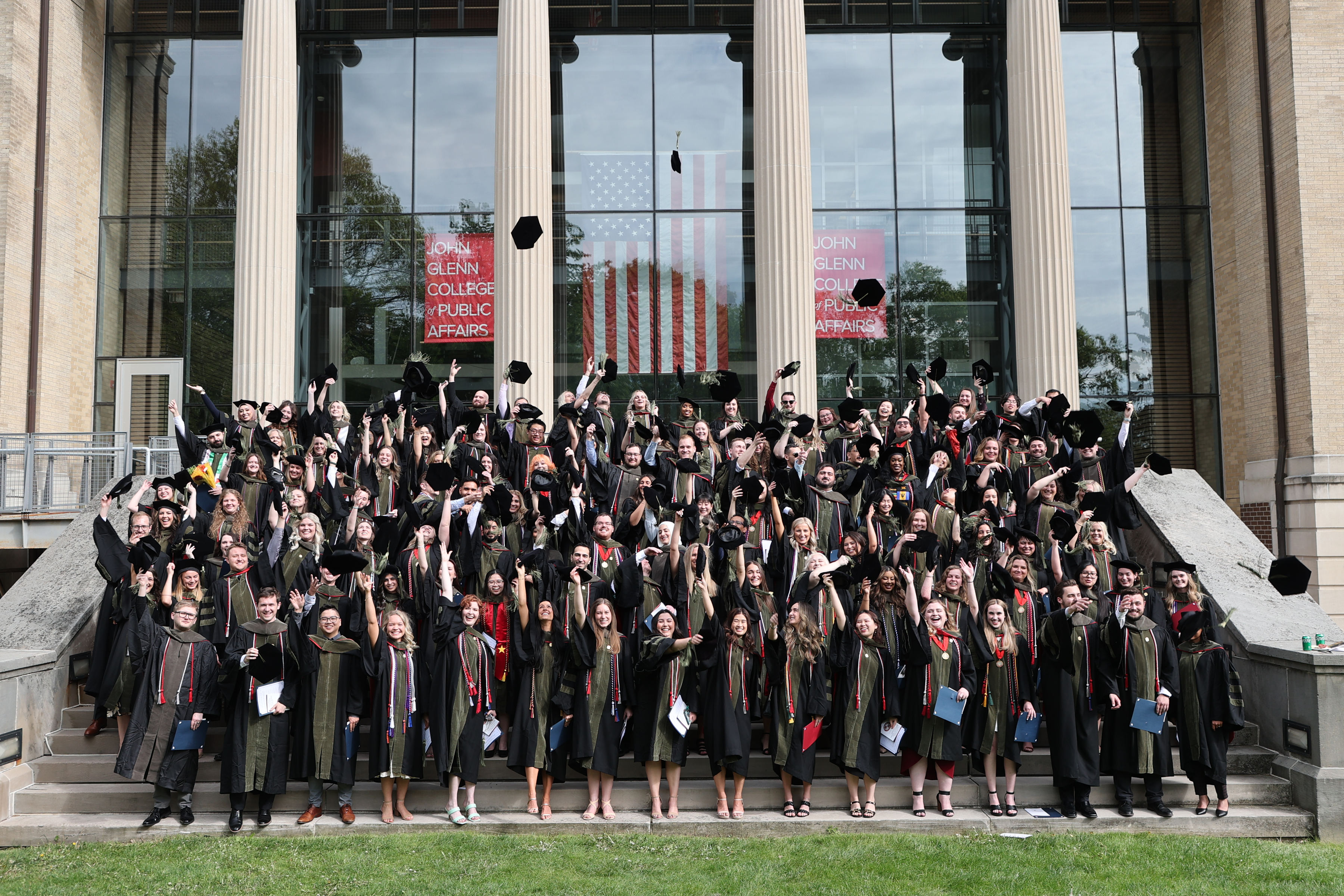 PharmD Class of 2023 on the steps of John Glenn College throwing their hats