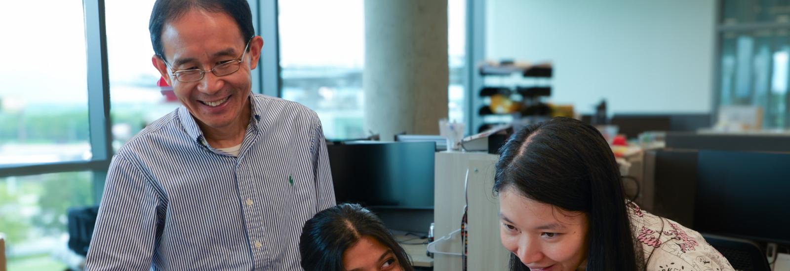 Researchers in the Cheng Lab gathered around a computer monitor