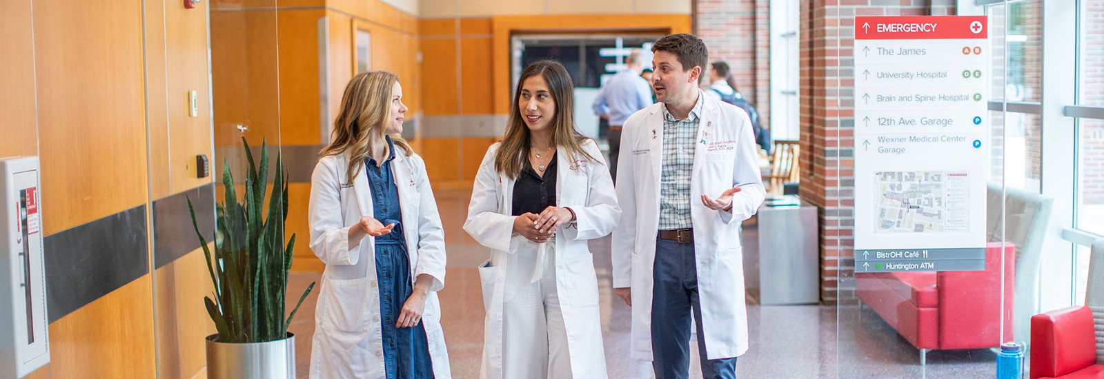 White coat students walking in a hospital corridor, talking amongst themselves.