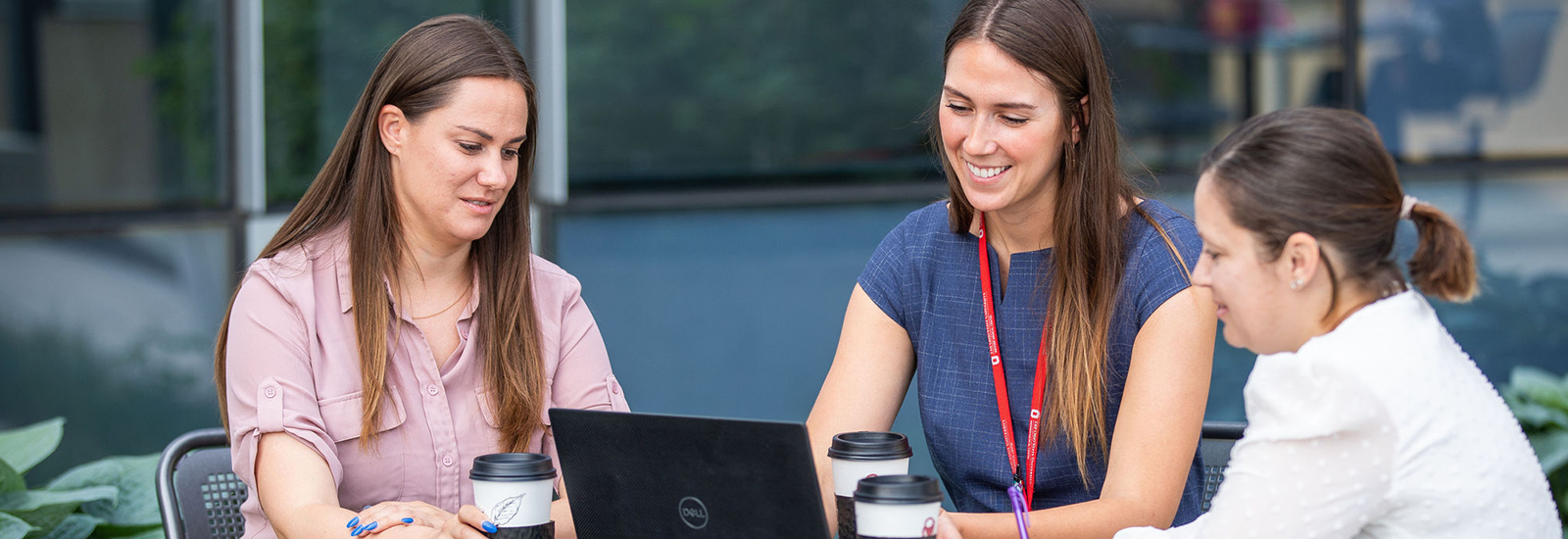 Group of graduate women sitting outside collaborating with each other.