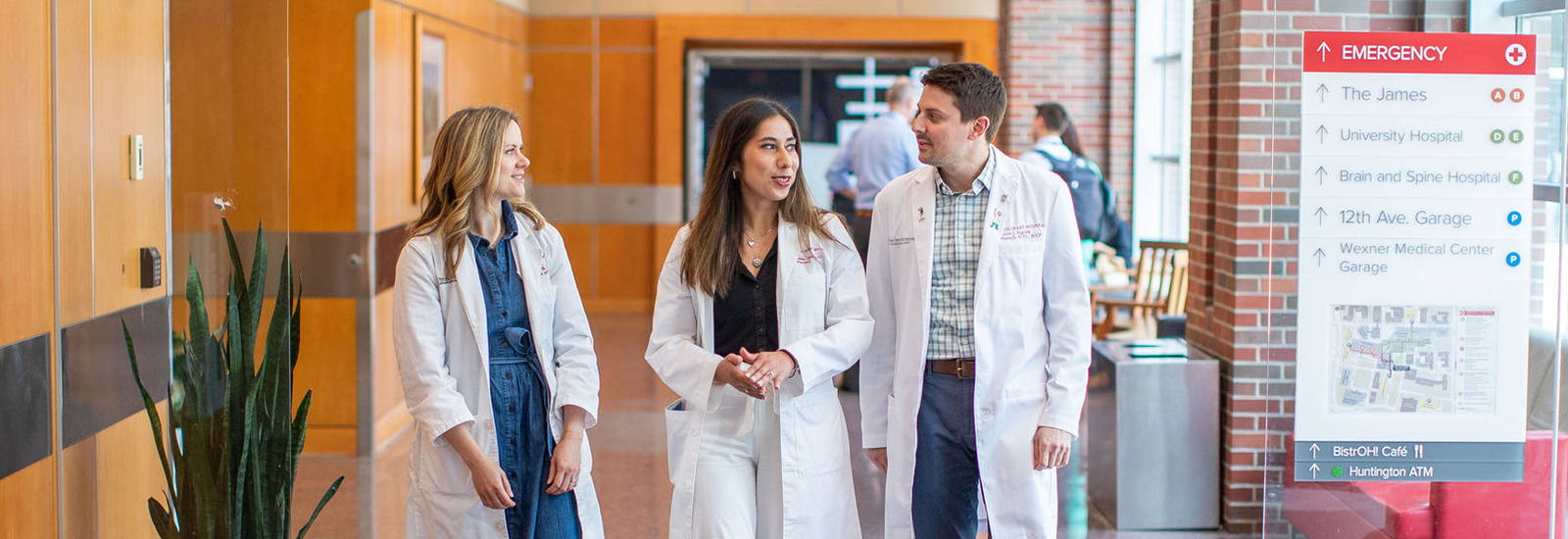 Graduate students in their white coats walking through a hospital