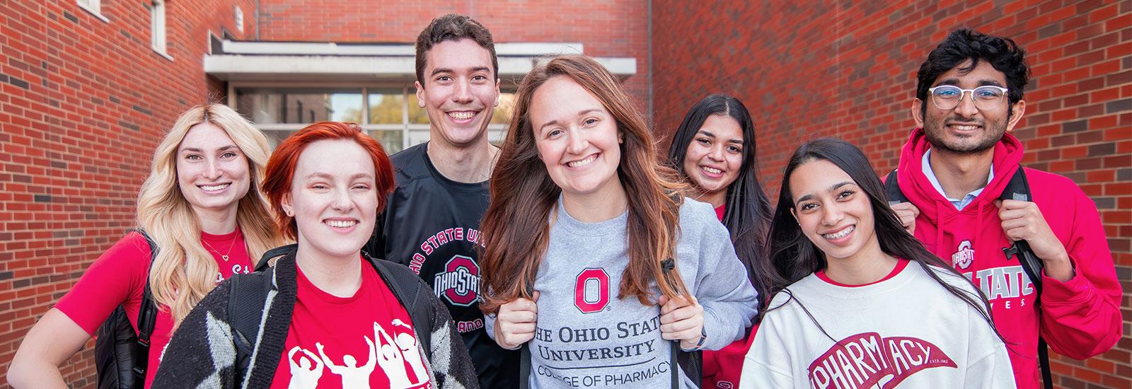 Image of multiple College of Pharmacy students smiling, huddled together outside of the Riffe Building