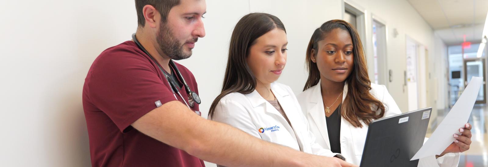 three doctors standing looking at computer