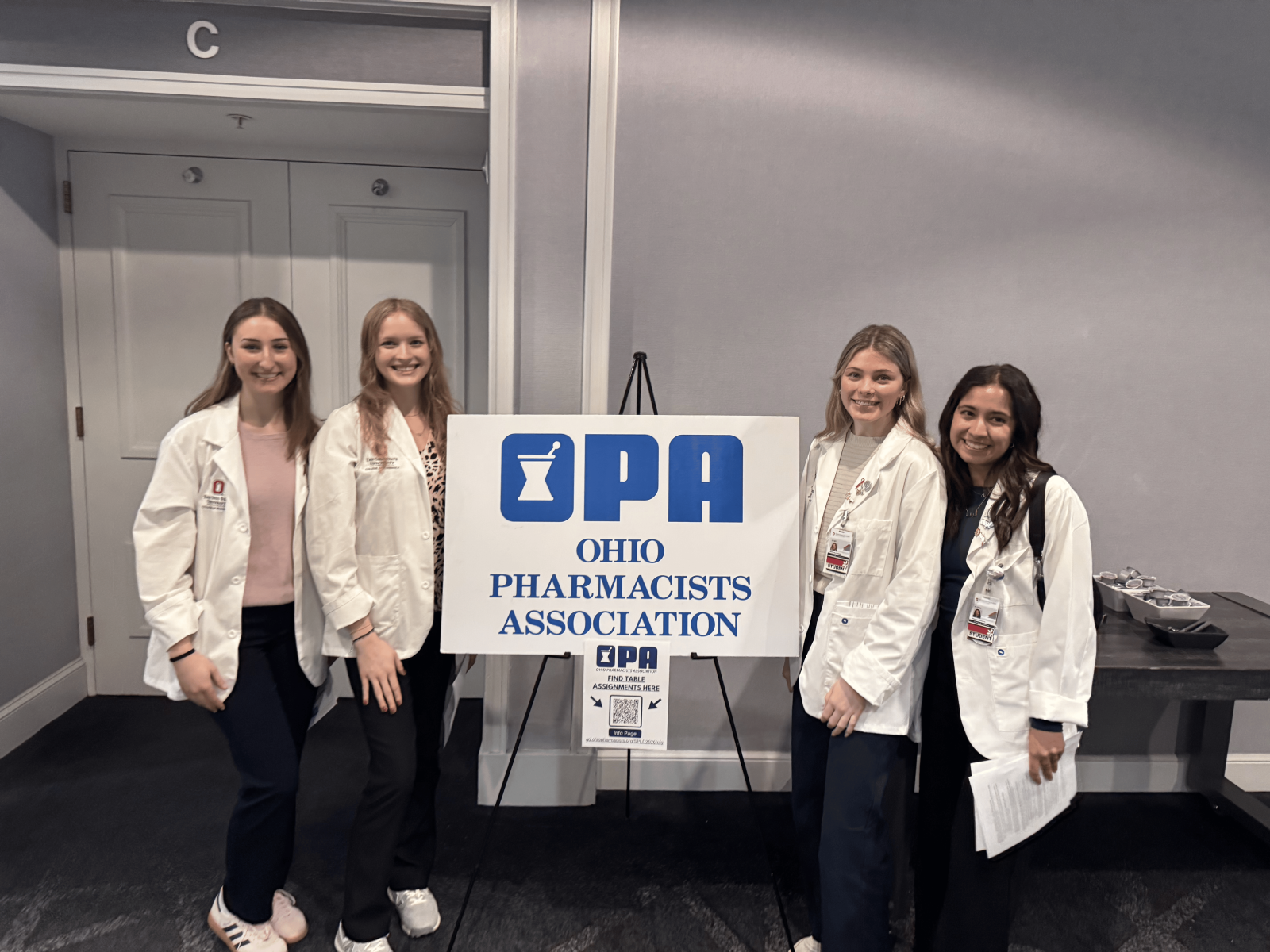 Four students, two on each side, of the OPA sign