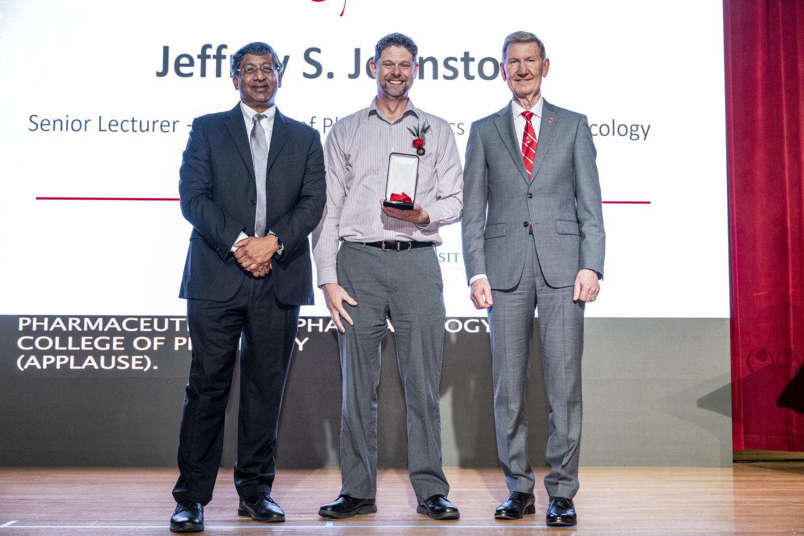 jeff johston receives award on stage with president and provost