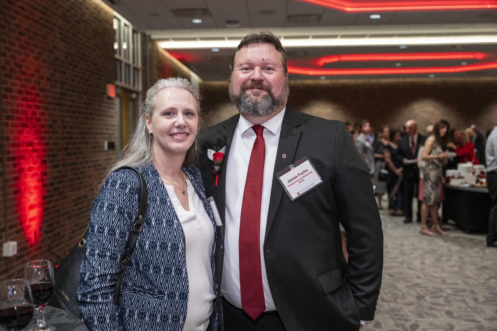 two people standing, posing for a photo at an event