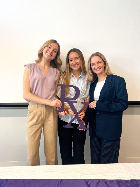 Three students holding the "Rx" sign