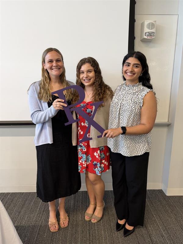 Three students holding the "Rx" sign