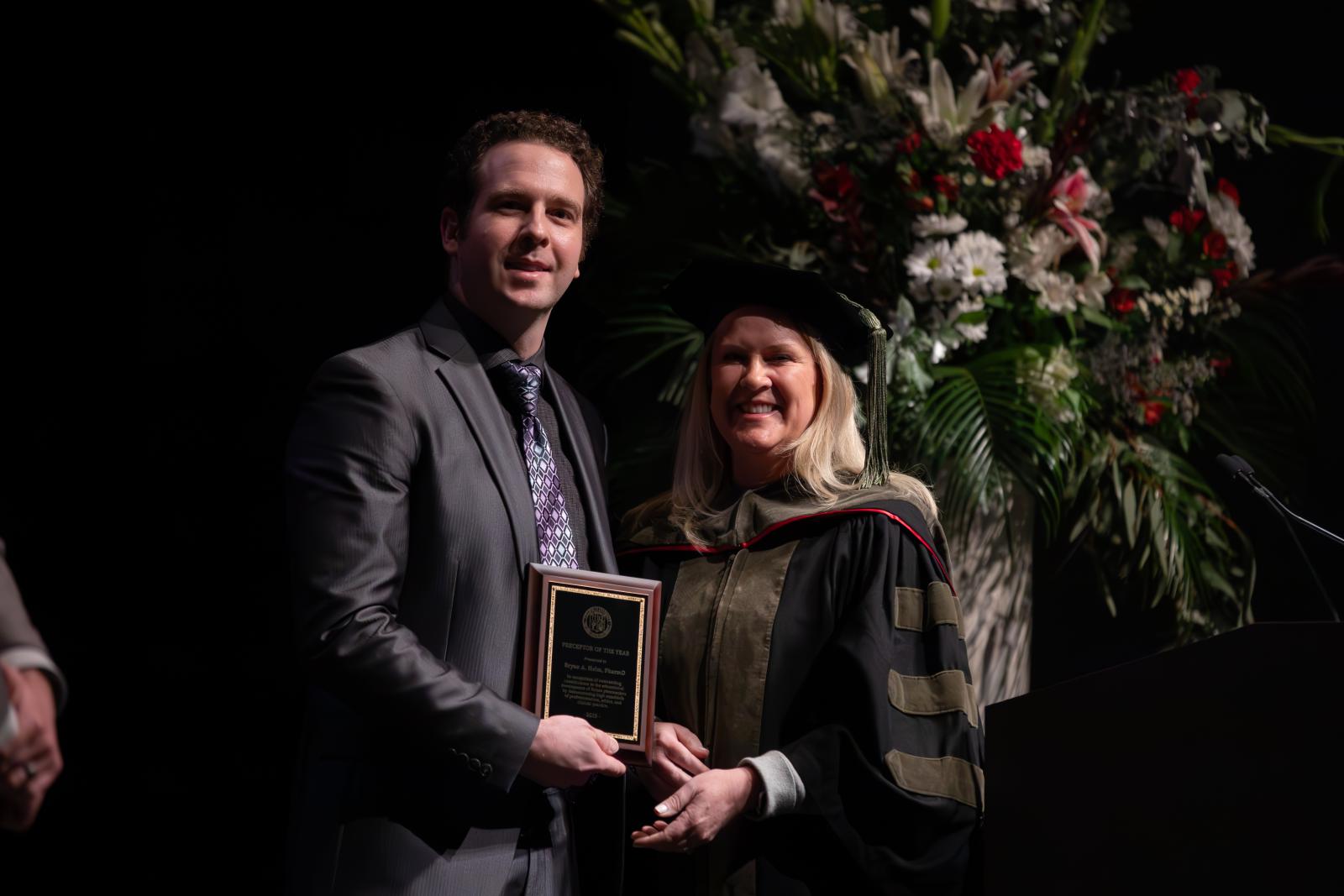 a man and a woman in regalia holding a plaque