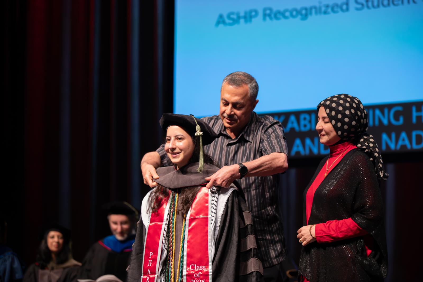 Tara Rikabi being hooded by her parents
