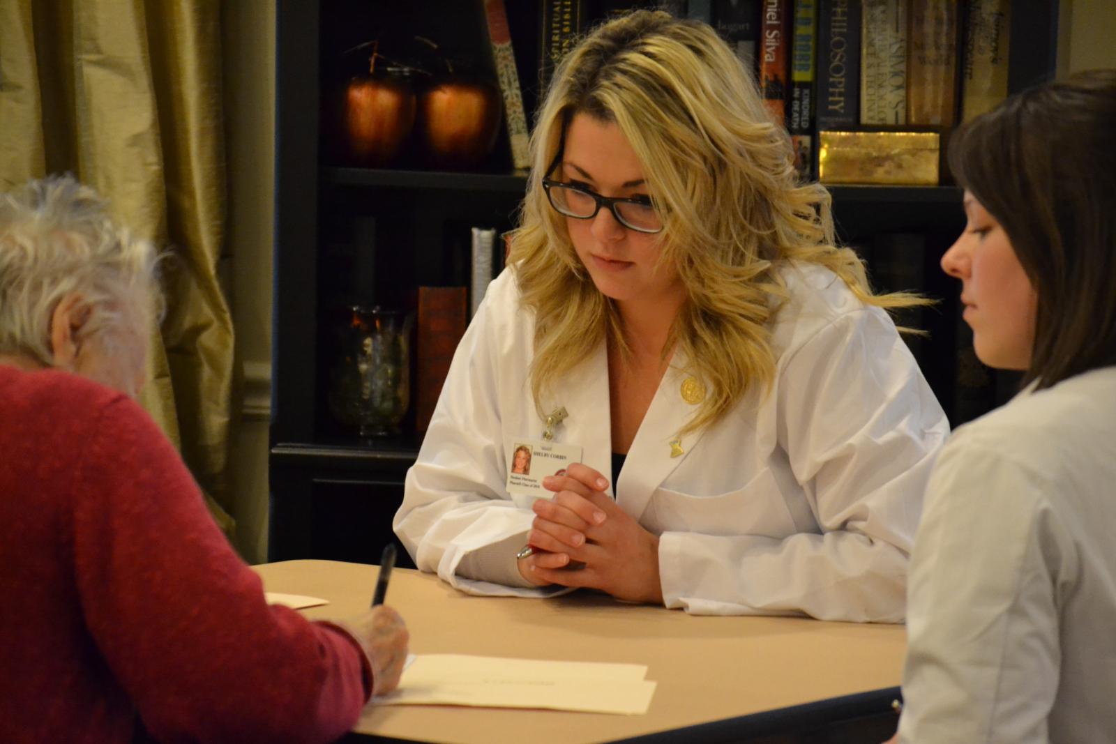 a pharmacy student and pharmacist consult a patient