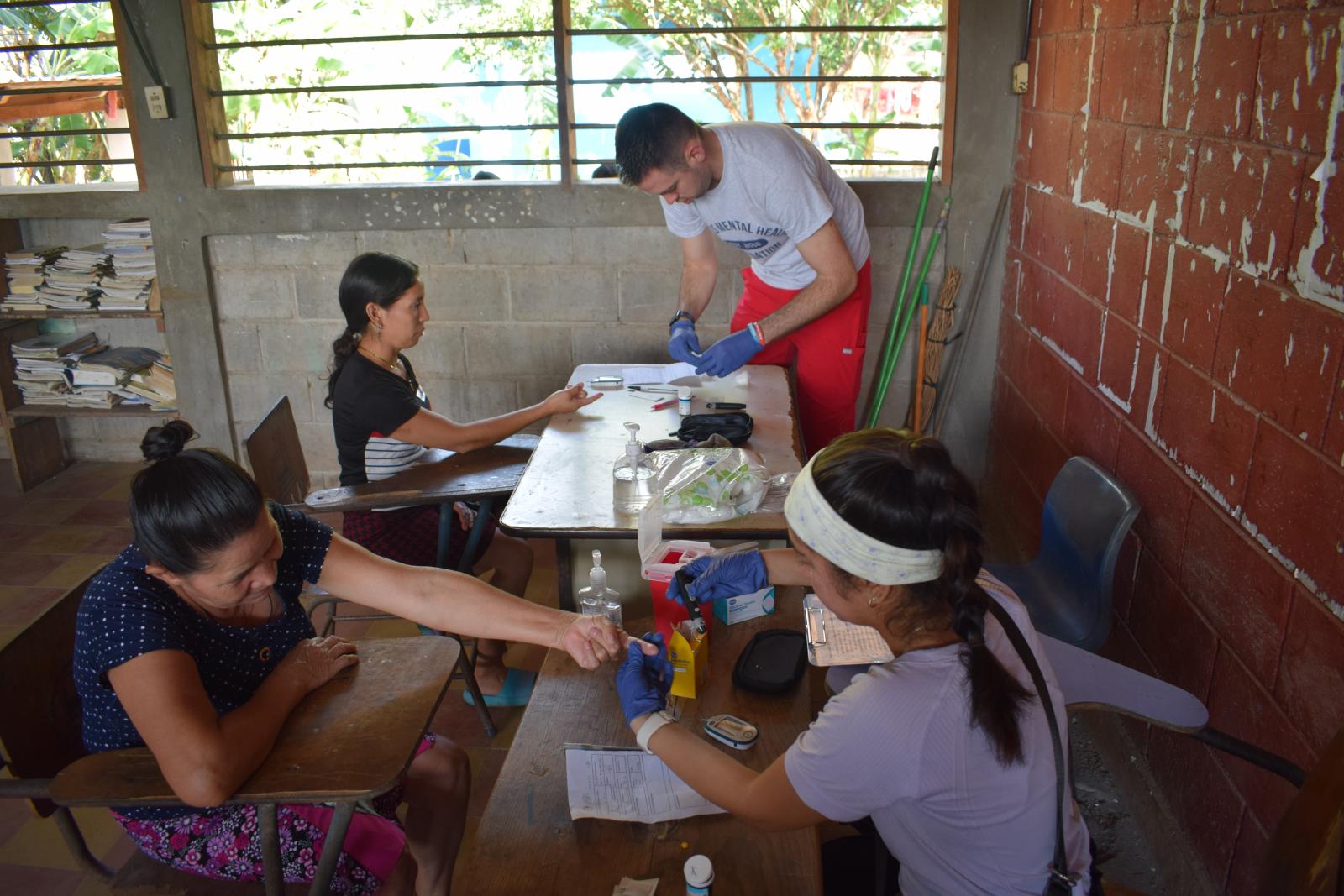 A man and a woman finger pricking two patients.
