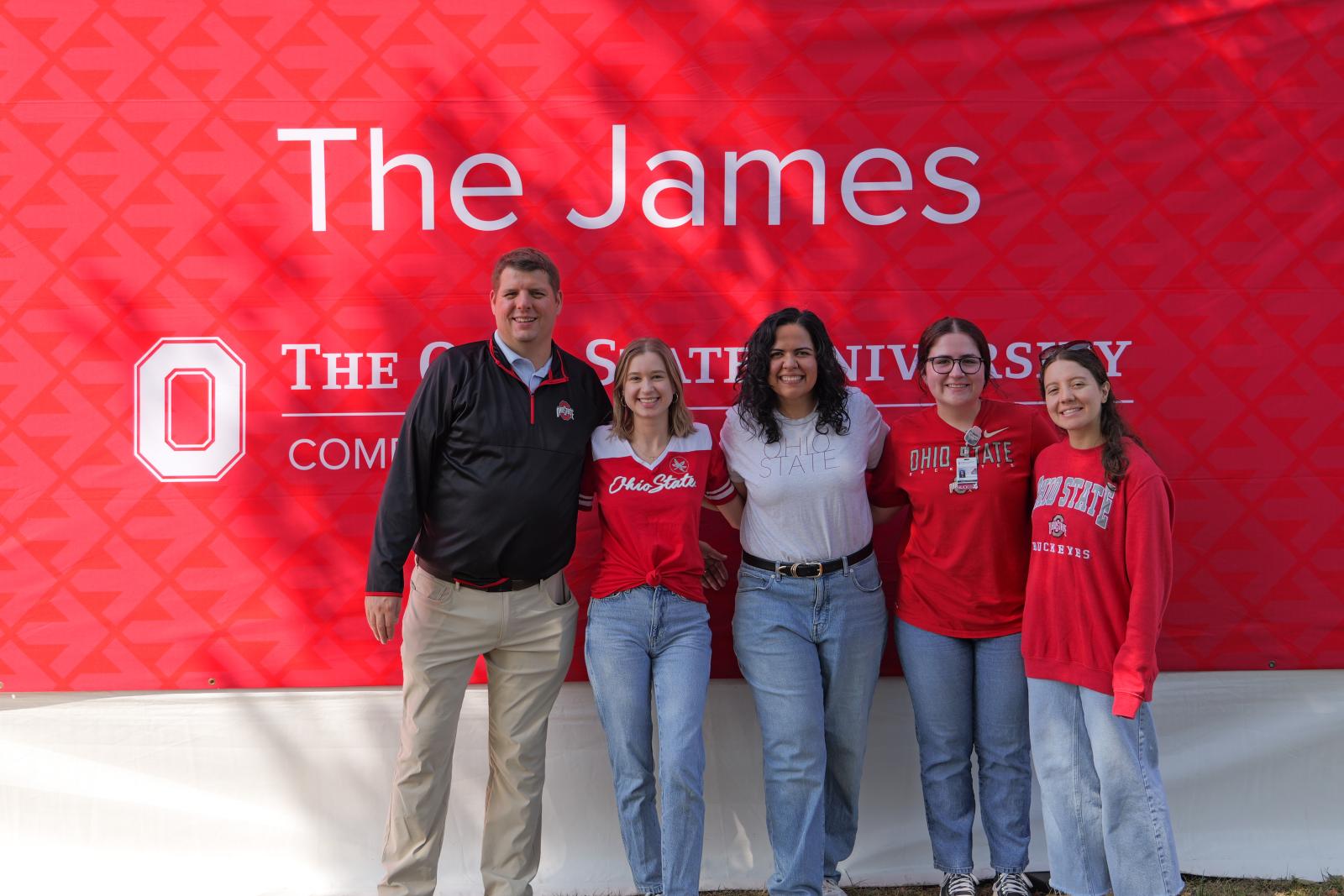 The vaccine education team posing for a group photo in front of a banner reading "The James"