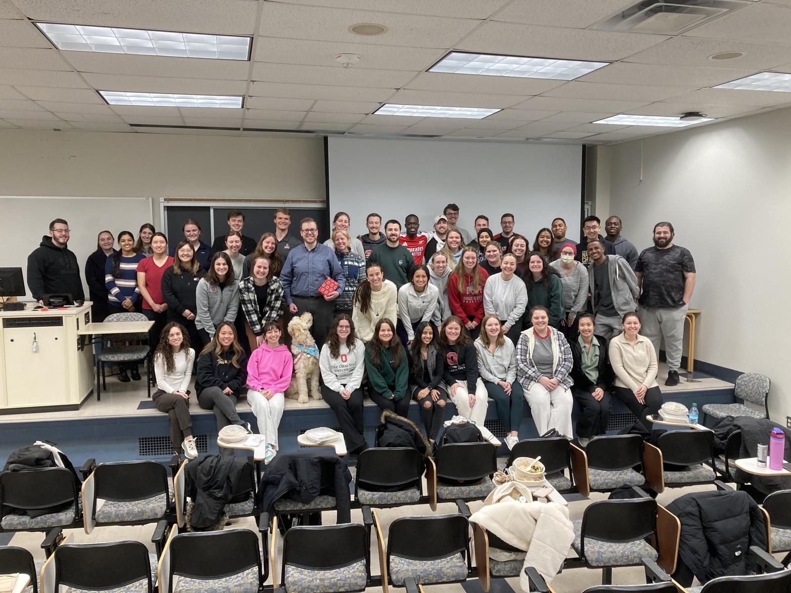 a large group of people pose in a lecture hall