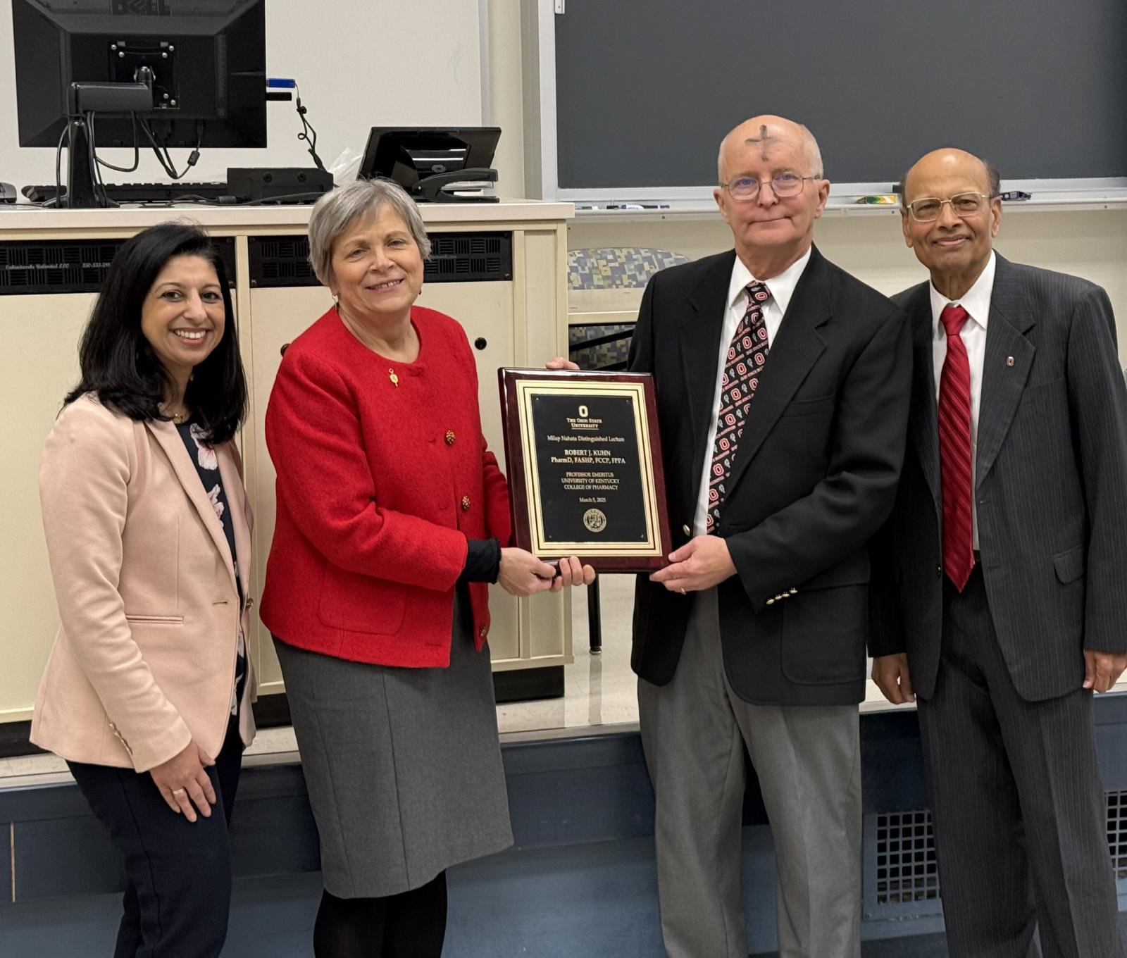 four people with a plaque