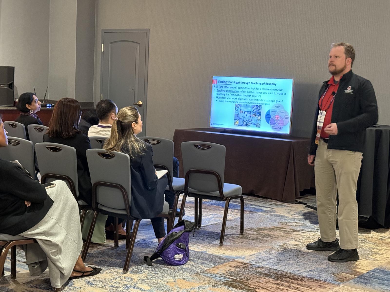 Dr. Denton presenting in front of a small crowd of people