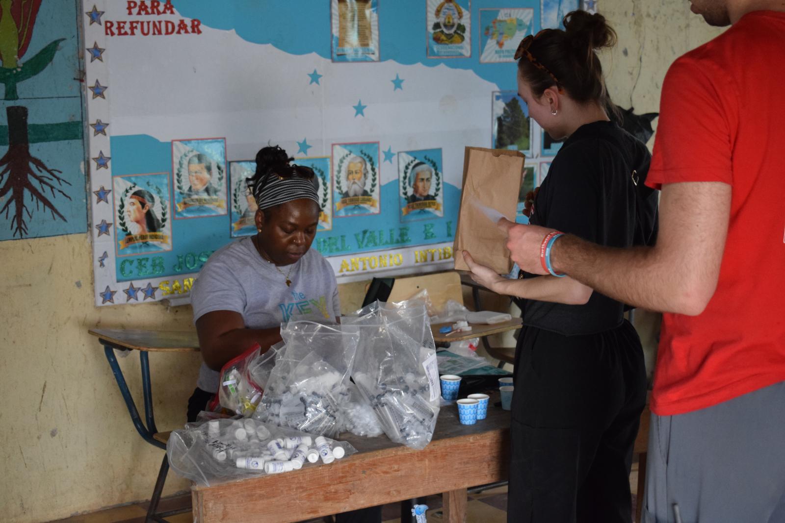 A woman in front of a table with empty syringes and medicine bottles.