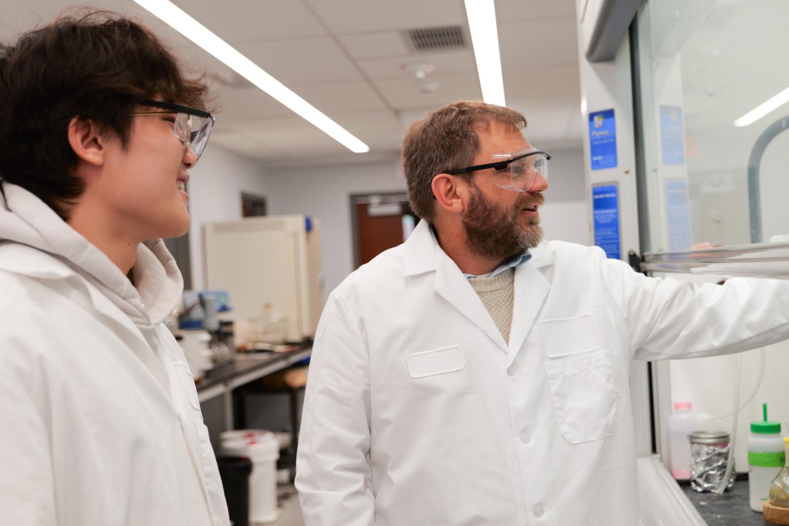 Dr. Mitton-Fry and student researcher Ayden He at a fume hood