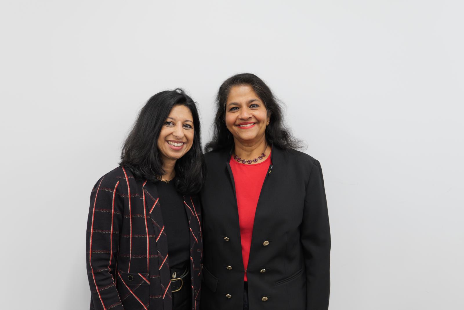 two women posing against a wall