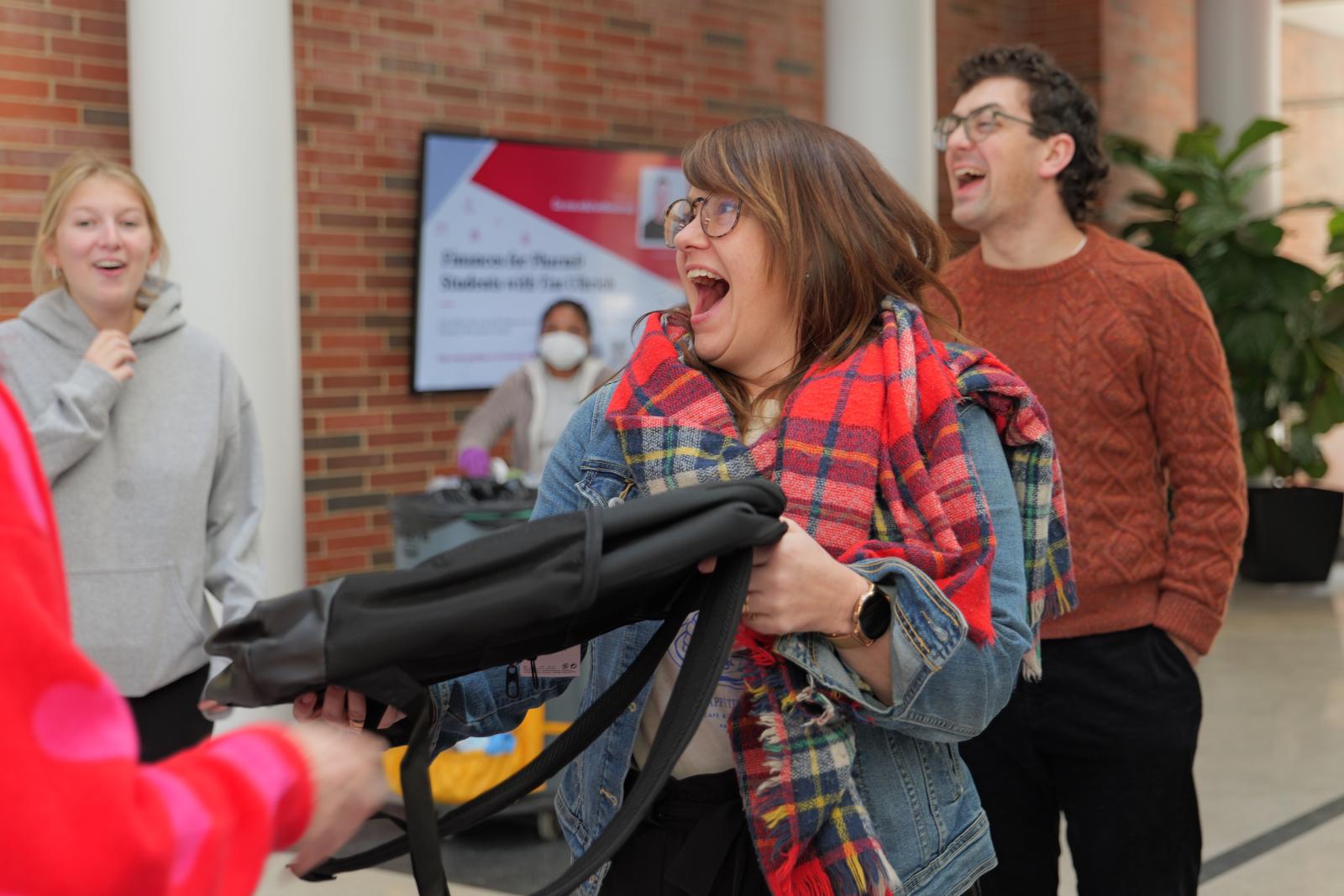 Staff member excitedly holding their bookbag
