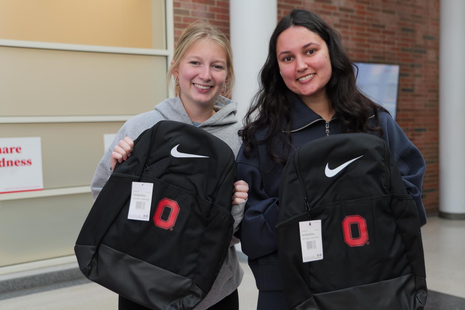 Two students holding up their bookbags