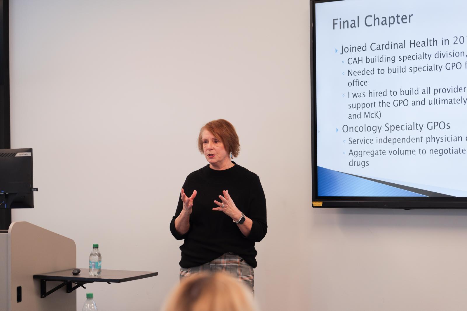 Dr. Valley speaking in front of a presentation slide. 