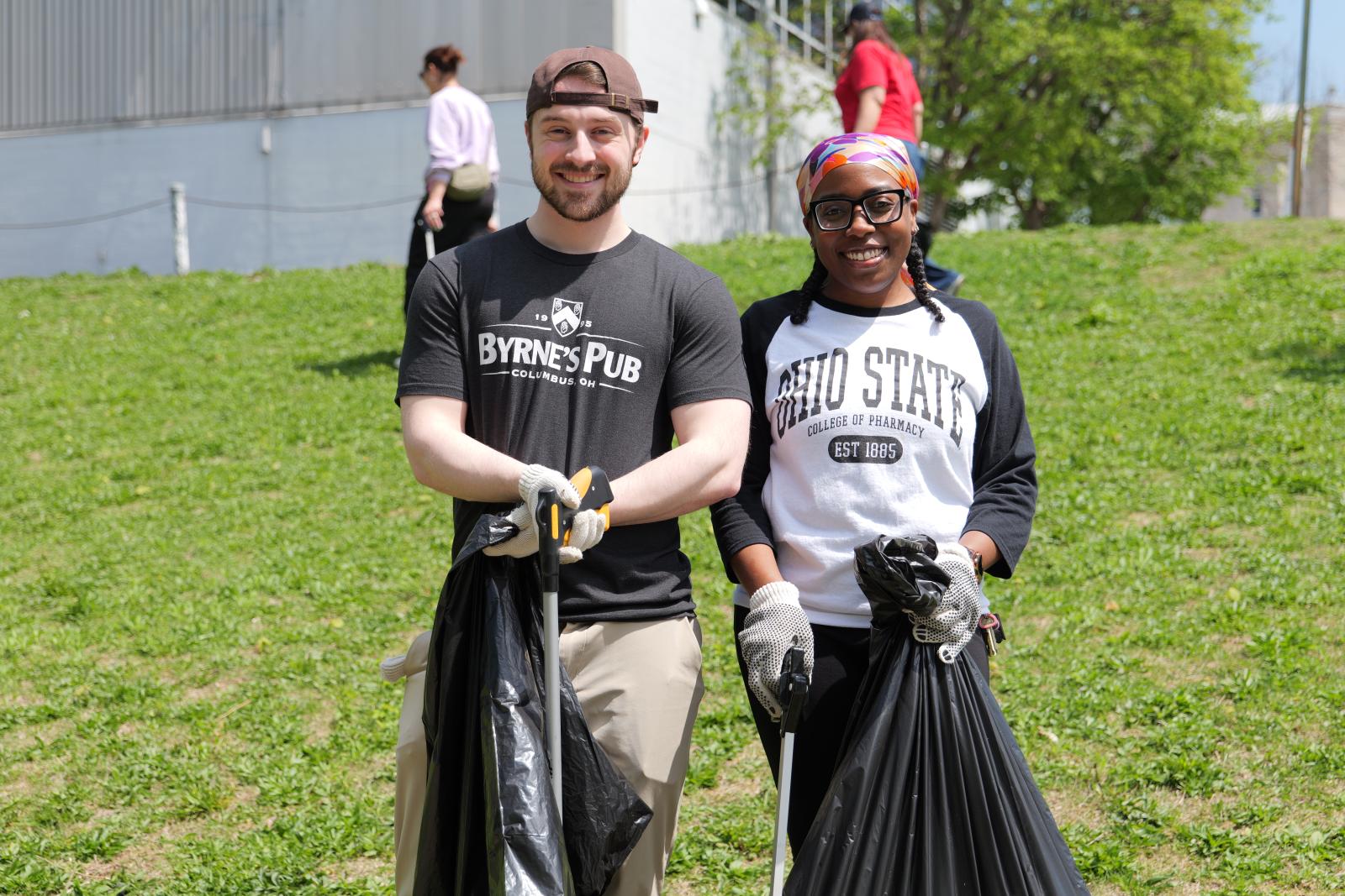 Two people holding their trash bags