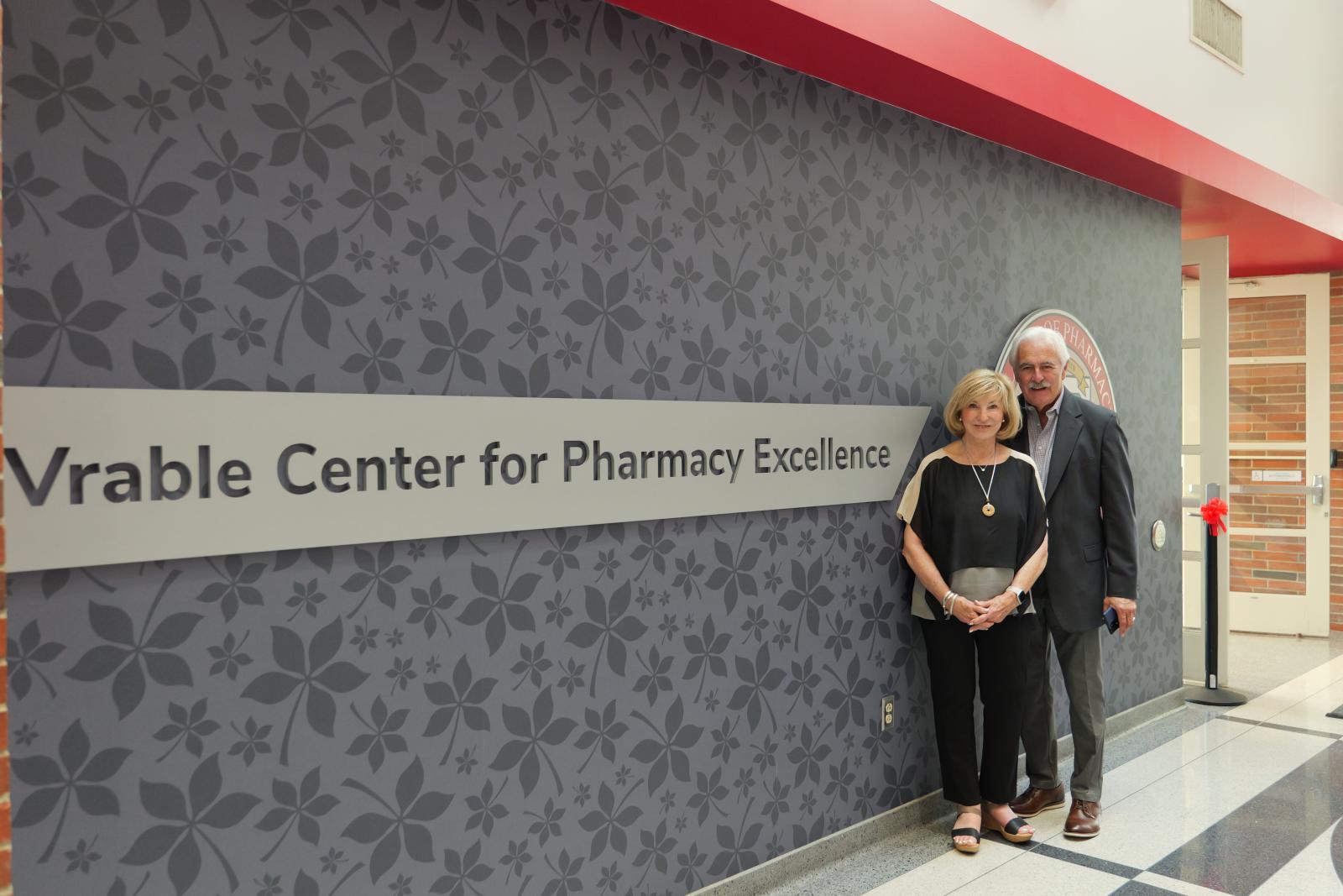 two people posing in front of a sign that read vrable center for pharmacy excellence