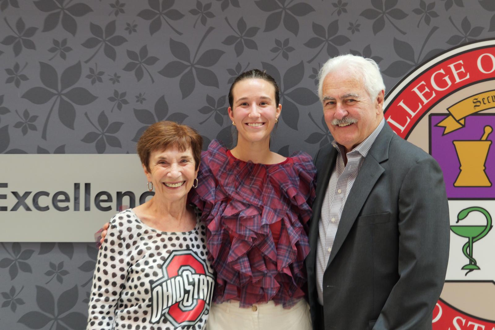three people posing in front of a wall
