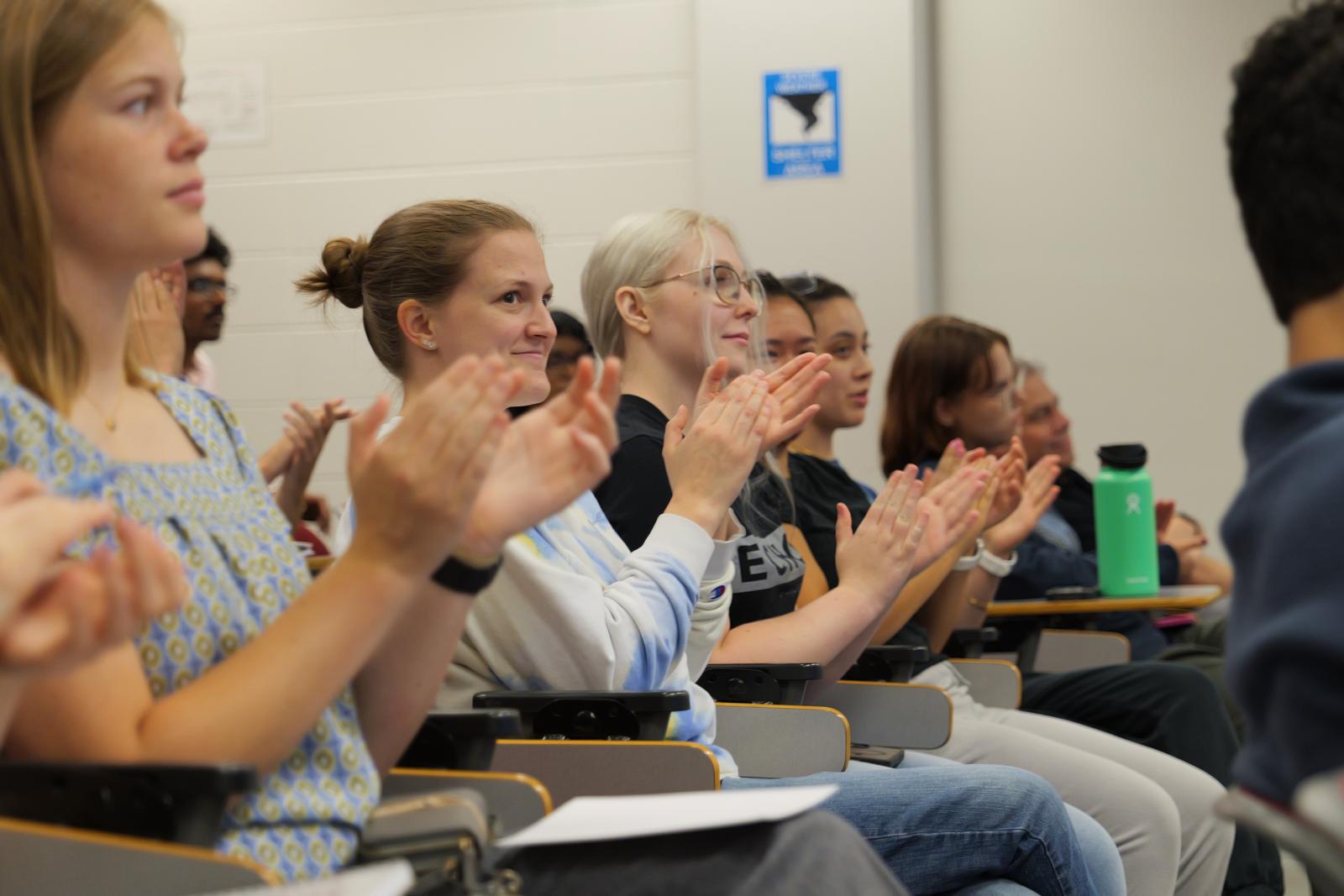Attendees applauding a research presentation