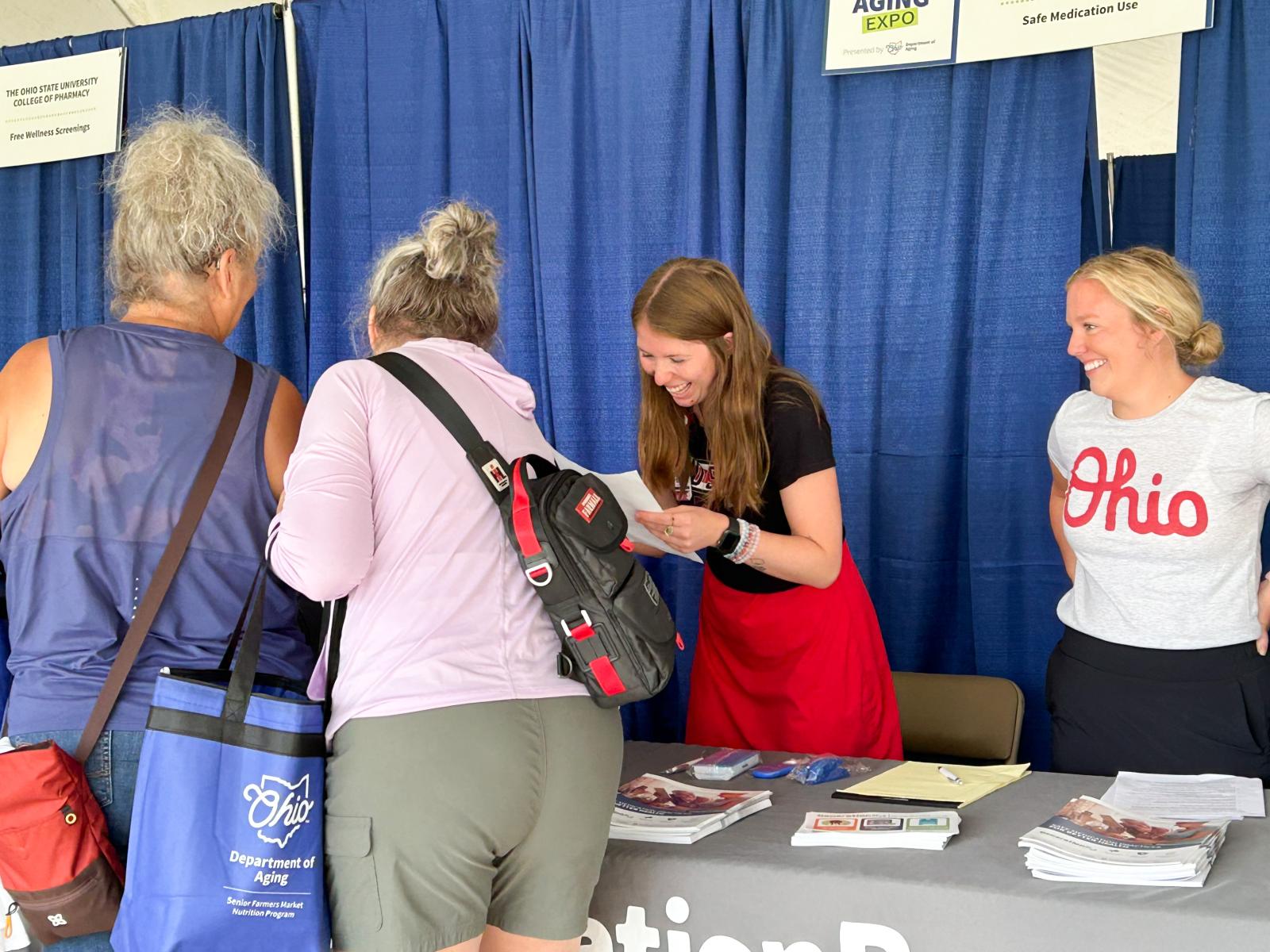 Students interacting with fair attendees at the Healthy Aging Expo