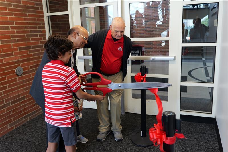 Ric and Dr. Nahata watching Dr. Nahata's grandson cut the ribbon
