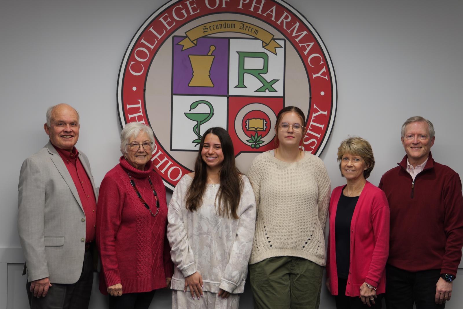 a group of people standing in front of the college seal