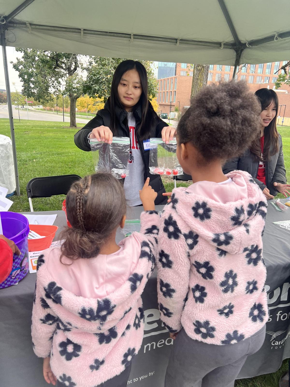 Two girls in matching sweaters choosing candy. 