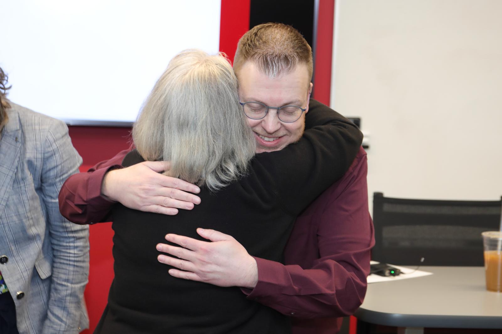 Dr. Matthews and an individual hugging 