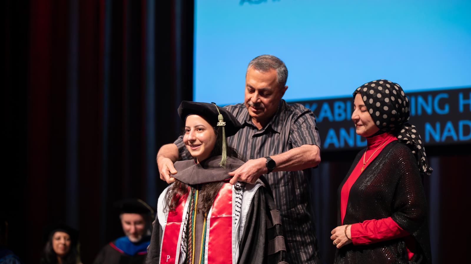 Tara Rikabi being hooded by her parents