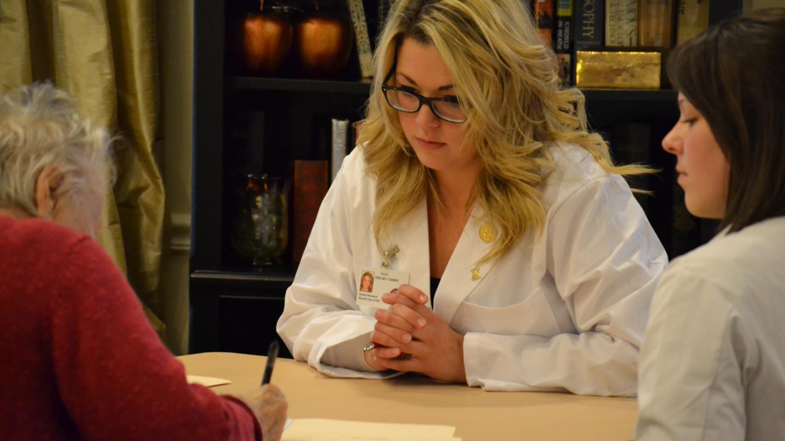 a pharmacy student and pharmacist consult a patient