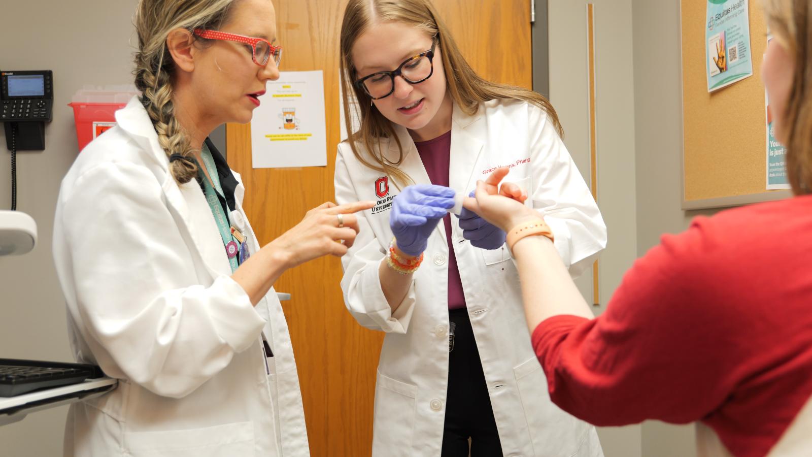 Preceptor showing resident how to perform finger stick