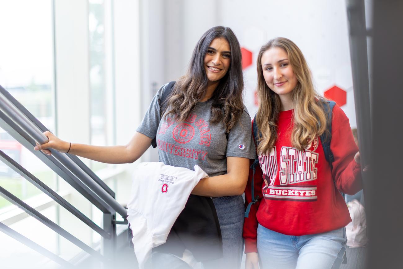 two students walking up the stairs smiling at camera