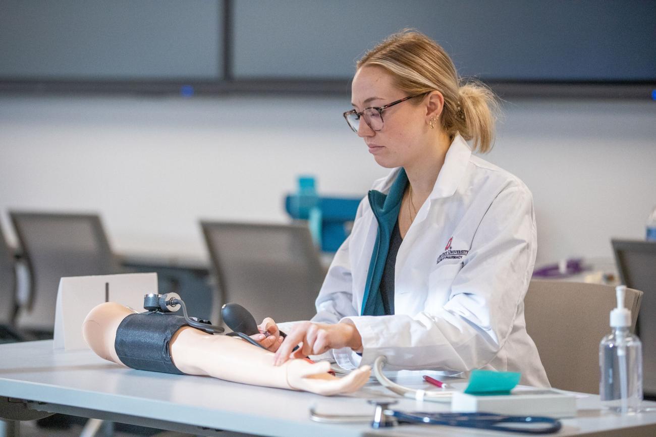 a pharmacy student simulating taking pulse