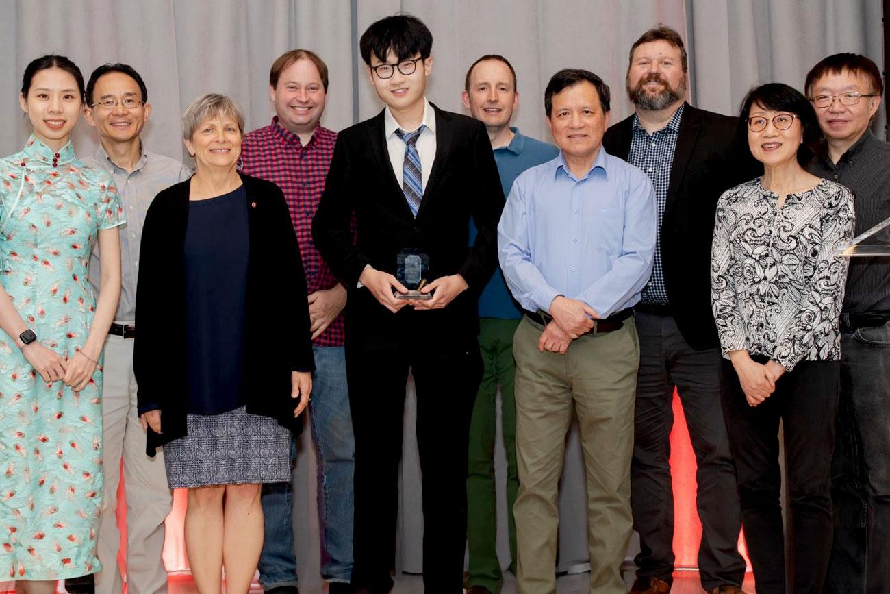 Sam Xing posing with his innovation award, celebrated by faculty and staff alongside him.