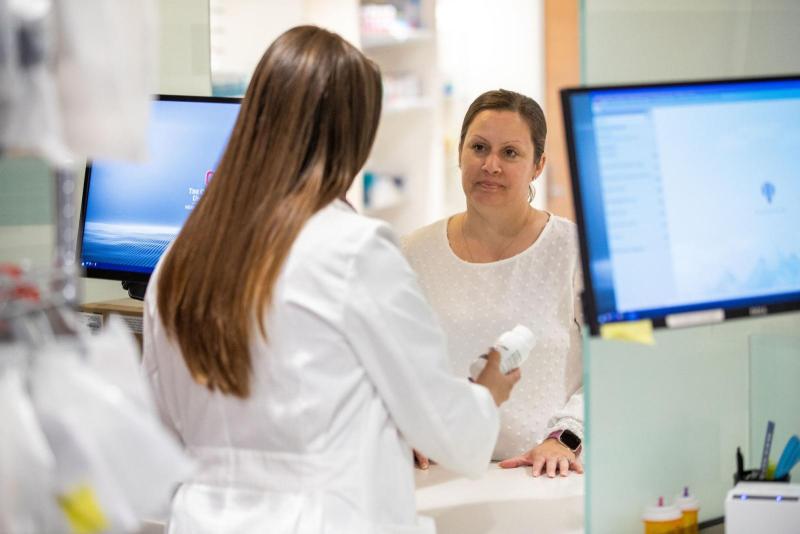 a patient at the counter talking to a pharmacist
