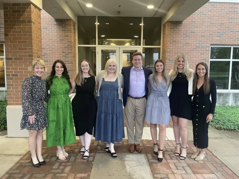 seven people posing outside a building