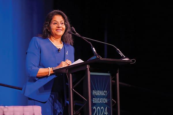 a person in blue blazer speaking at a podium