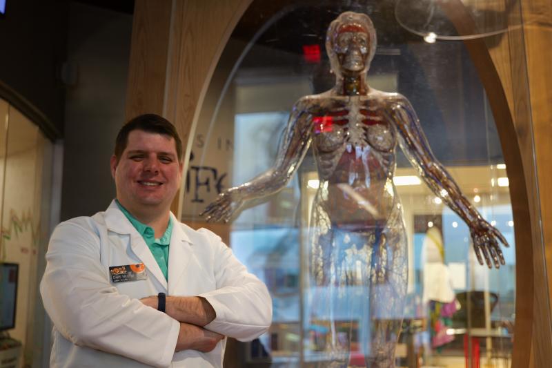 professor in lab coat next to skeleton model