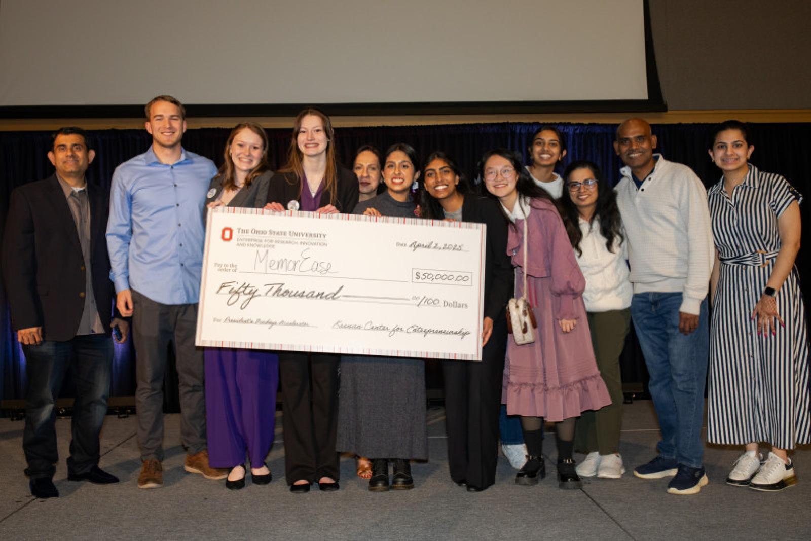 a group of people on stage holding a large check