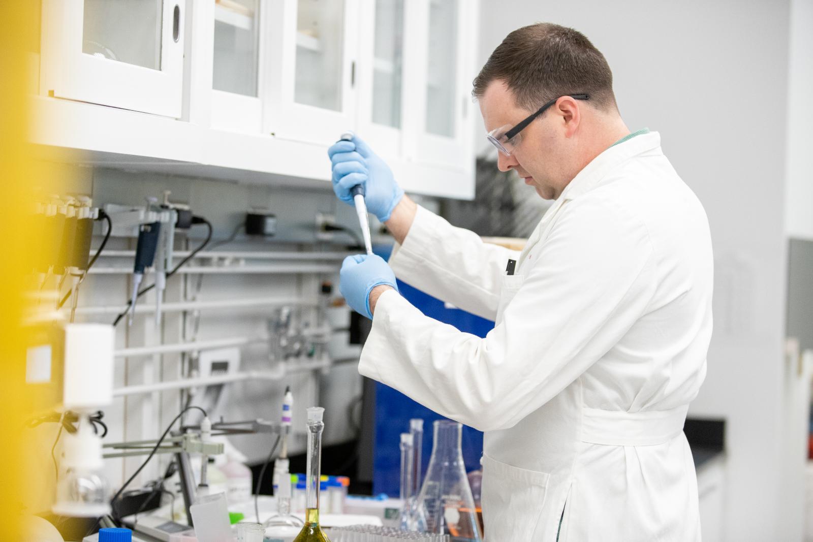 Dr. Binzel using a pipette at a lab bench