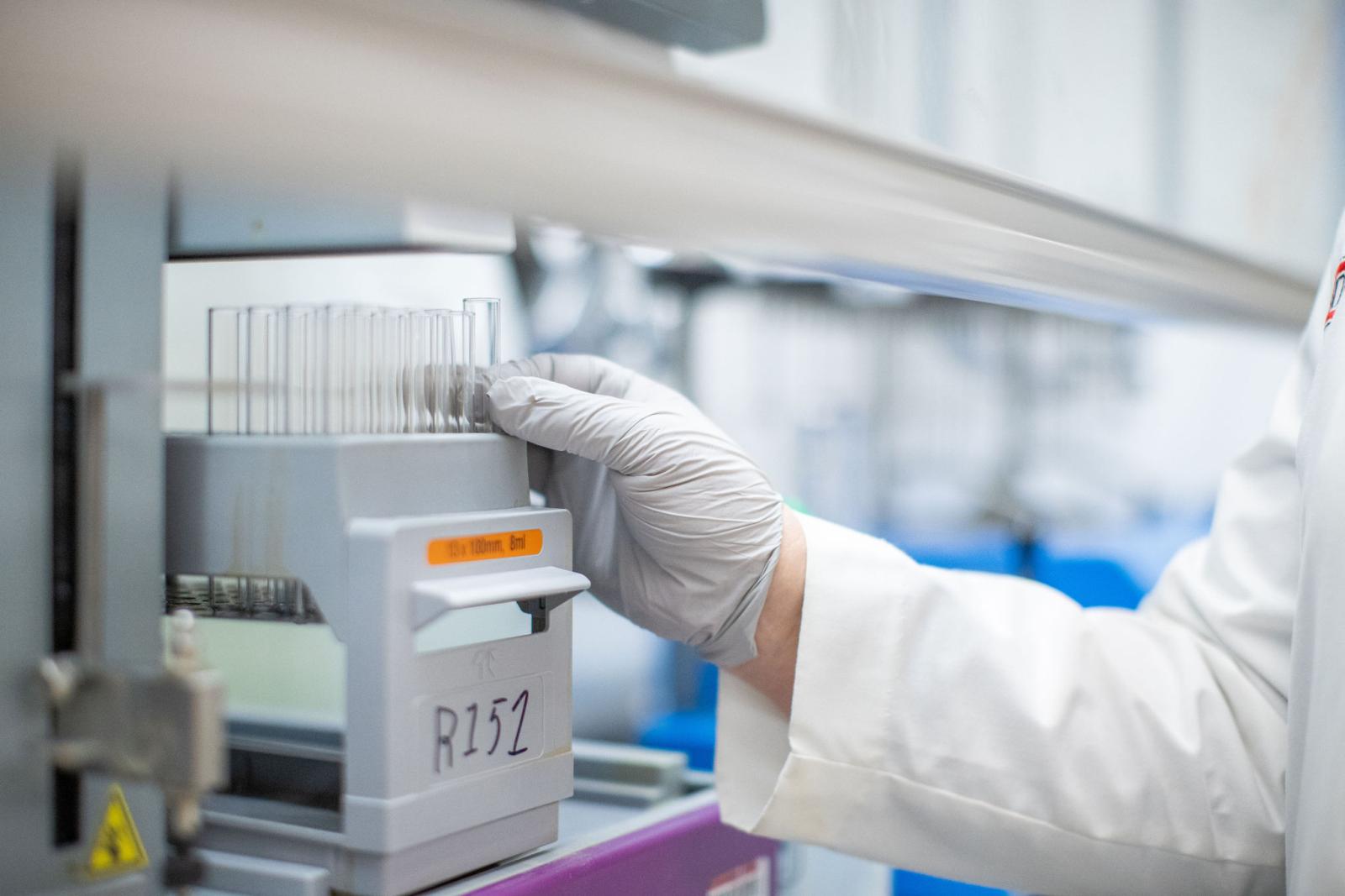 a researcher's gloved hand grabbing for viles